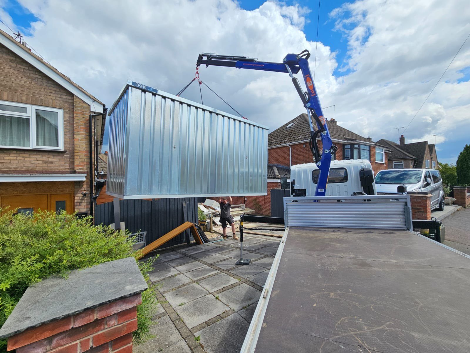IP&G crane lorry placing a container in a driveway